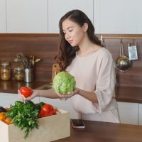 台所で野菜を持つ女性