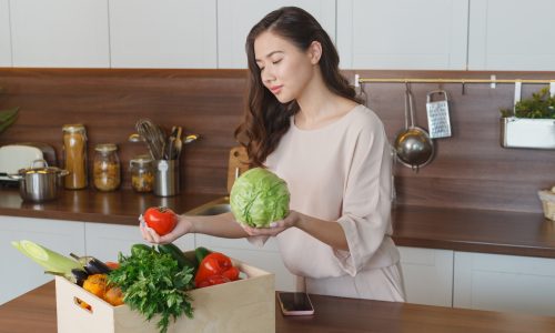 台所で野菜を持つ女性